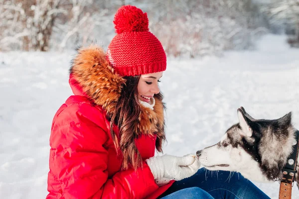 Jovem mulher brincando com seu cachorro Husky no parque de inverno — Fotografia de Stock