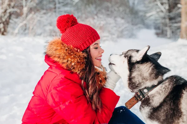 Jovem mulher brincando com seu cachorro Husky no parque de inverno — Fotografia de Stock