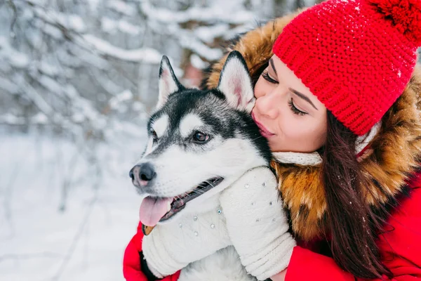 Kvinnan smeker Husky hunden i vinter skog — Stockfoto