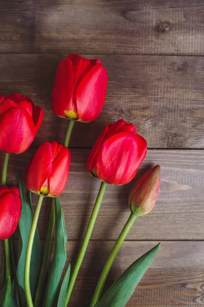 Rij met rode tulpen op houten achtergrond met ruimte voor bericht. Moeders dag achtergrond. Bovenaanzicht. — Stockfoto