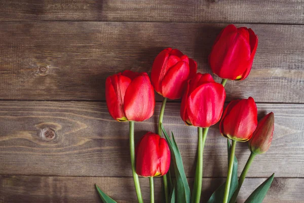 Rij met rode tulpen op houten achtergrond met ruimte voor bericht. Moeders dag achtergrond. Bovenaanzicht. — Stockfoto