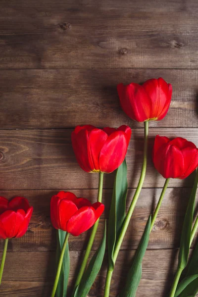 Mooie rode tulpen op bruin houten achtergrond met ruimte voor tekst. Bovenaanzicht, plat lag. — Stockfoto