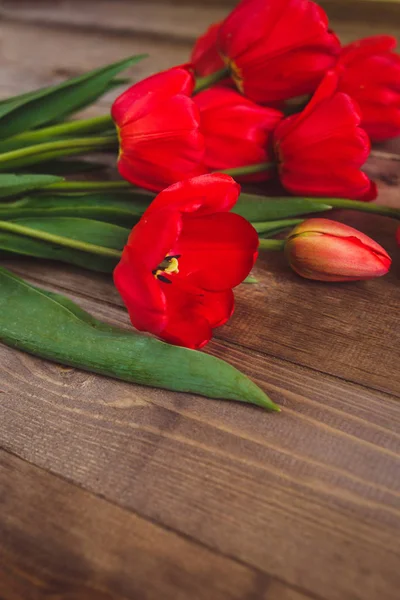 Rij met rode tulpen op houten achtergrond met ruimte voor bericht. Moeders dag achtergrond. Bovenaanzicht. Plat leggen — Stockfoto