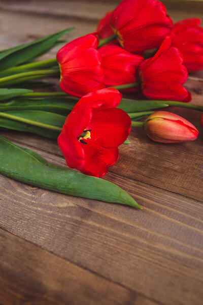 Row of red tulips on wooden background with space for message. Mothers Day background. Top view. Flat lay