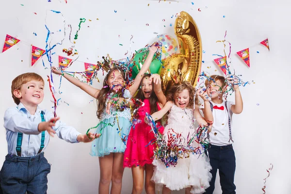 Grupo de crianças bonitas jogando confete colorido e olhando feliz na festa de aniversário — Fotografia de Stock