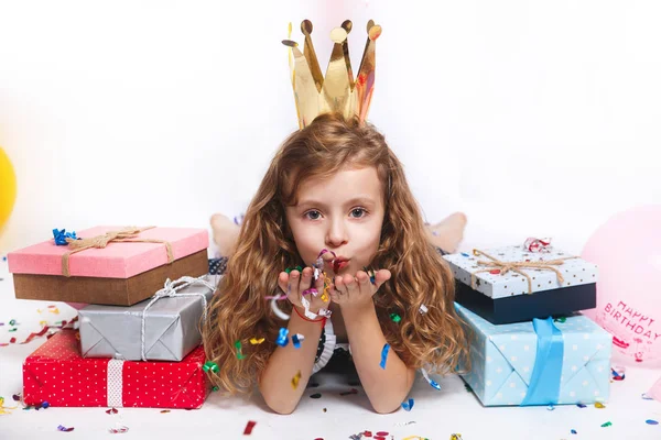 Festa de aniversário para uma criança bonita. Menina soprando confete colorido e olhando feliz na festa de aniversário — Fotografia de Stock