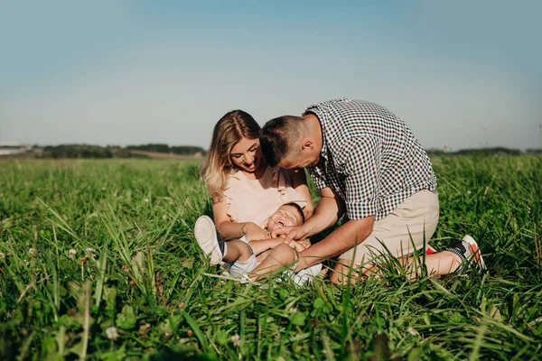 Familia feliz disfrutando juntos en el día de verano. Familia sentada en la hierba y divertirse — Foto de Stock