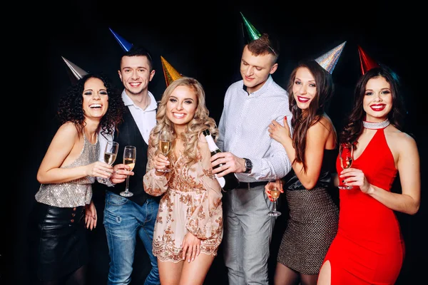Amigos a fazer uma grande festa à noite. Seis pessoas se divertindo e bebendo champanhe no fundo preto — Fotografia de Stock