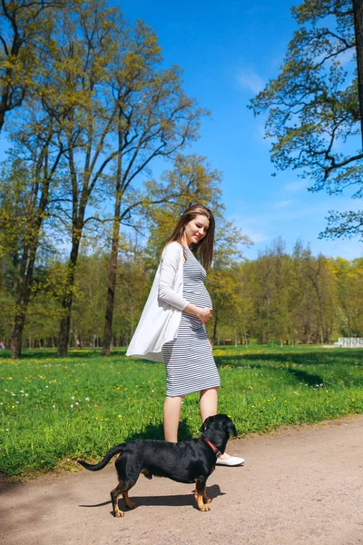 Gravid kvinna att vidröra hennes stora mage och promenader i parken — Stockfoto