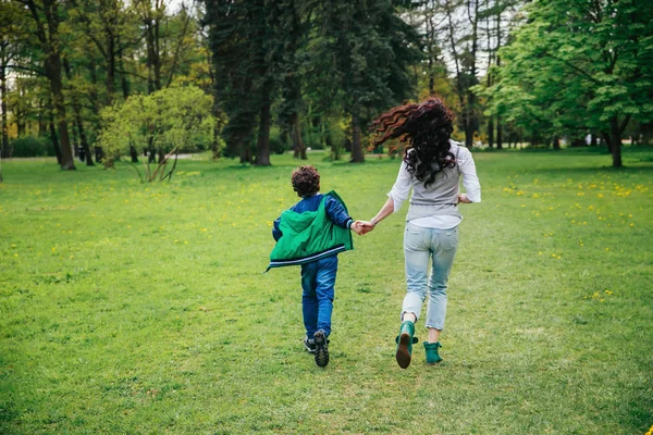 Joven madre corriendo con el niño en el día soleado en el parque . — Foto de Stock