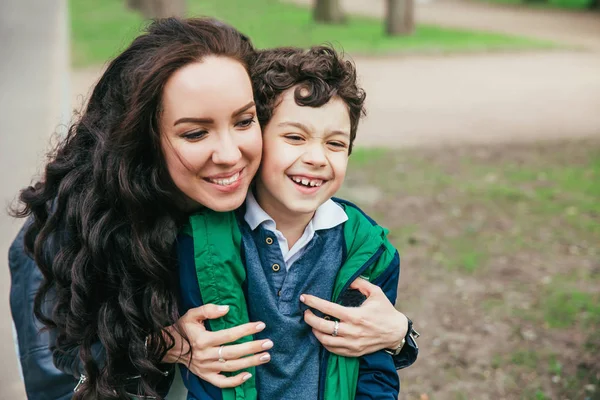 Familia feliz en el parque de primavera. Joven madre y su hijo pasar tiempo al aire libre en un día de verano — Foto de Stock