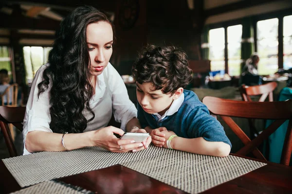 母亲与小可爱的男孩一起使用智能手机在餐厅 — 图库照片