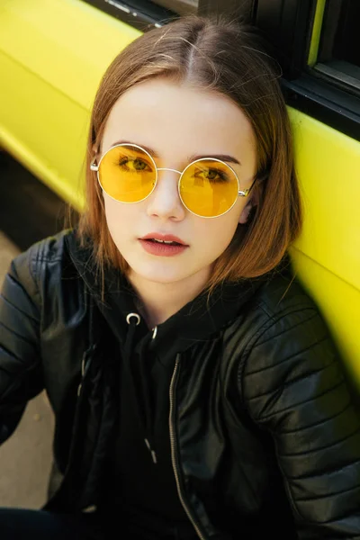 Güzel moda genç kız güneş gözlüğü ve Sarı Arabayı açık poz deri ceket — Stok fotoğraf