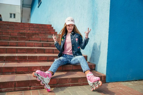 Adolescente chica en patines sentado en el paso en la ciudad — Foto de Stock