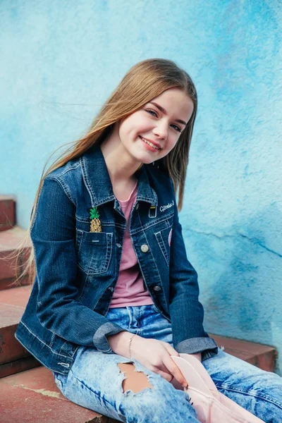 Ritratto primo piano bella adolescente sorridente in cappello e giacca di jeans sopra la parete blu — Foto Stock