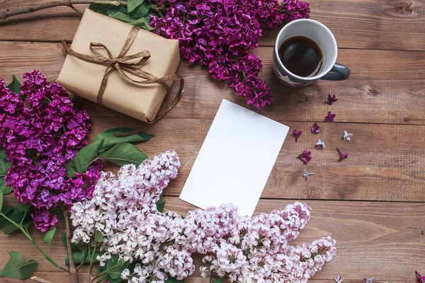 Ramillete de flores lila sobre mesa de madera con tarjeta en blanco para texto, regalo, café. Puesta plana — Foto de Stock