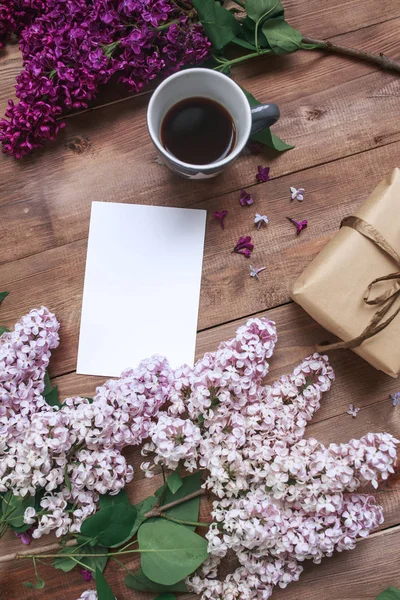 Ramillete de flores lila sobre mesa de madera con tarjeta en blanco para texto, regalo, café. Puesta plana —  Fotos de Stock