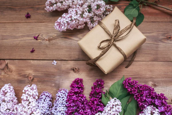 Ramo de flores lila sobre tablones de madera con regalo . — Foto de Stock