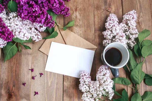 Ramillete de flores lila sobre mesa de madera con tarjeta en blanco para texto, regalo, café. Puesta plana — Foto de Stock