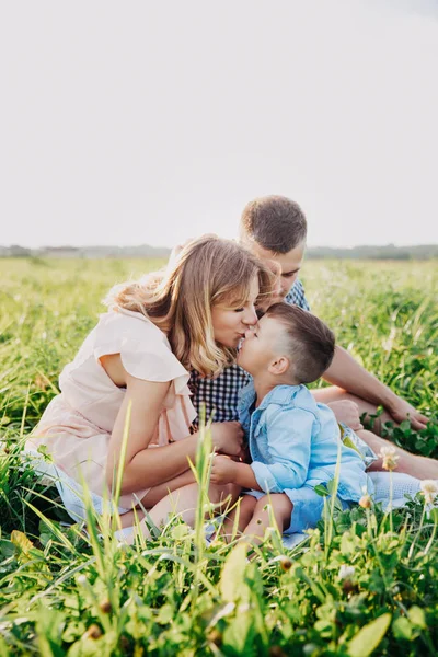 Familia feliz disfrutando juntos en el día de verano. Pequeño hijo besando a su madre — Foto de Stock