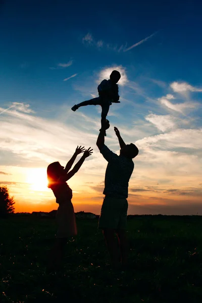 夕暮れ時、小さな子供と幸せな家族、一緒に親。空気中を上げる赤ちゃんを父します。. — ストック写真