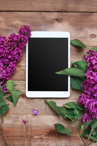 Boeket van lila bloemen op houten tafel met Tablet. Bovenaanzicht — Stockfoto