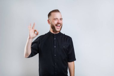 Gri arka plan üzerinde ok sembolü gösteren modern saç modeli ile neşeli yakışıklı dost adam portre yakın