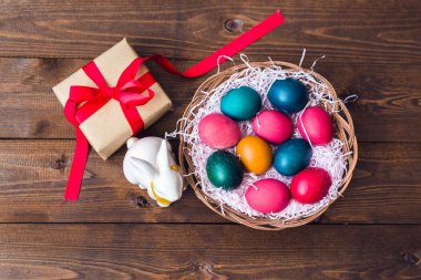 ahşap arka plan üzerinde renkli yumurta hasır sepet, hediye ve bunny kapat