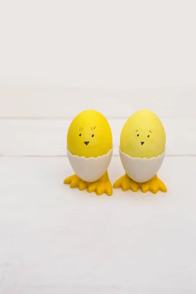 Funny yellow Easter Eggs with different faces and feets on wooden background
