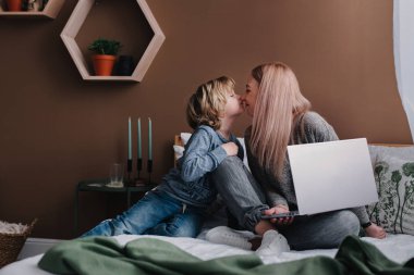 Kadın Freelancer evde taşınabilir dizüstü bilgisayar kullanarak oğlu wiith tıklandığını