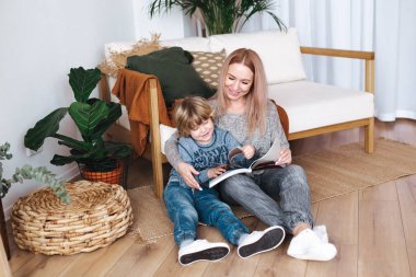 Anne ve küçük oğul oturan ve okuma kitap birlikte evde