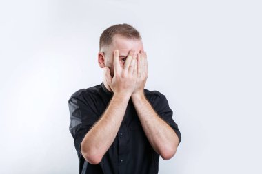 Genç adam parmak olsa peeks, her iki eliyle yüzünü kapsar