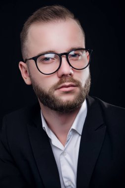 Smart serious businessman with glasses posing on black background. Studio shoot