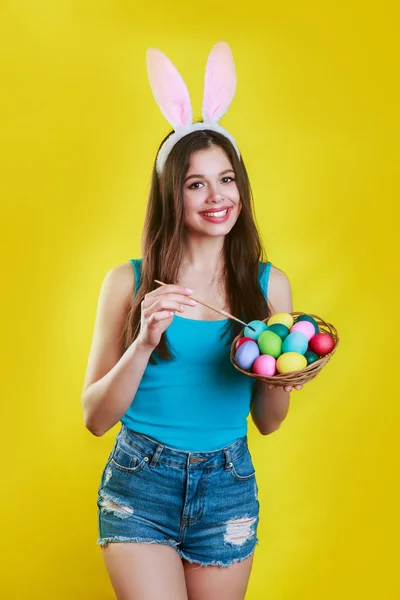 Painting egg. . Easter Day. Rabbit woman. Bunny costume. Smiling woman with bunny ears painting egg
