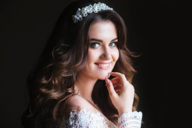 Düğün gününde odada gülümseyen zarif gelinlik ve diadem koyu uzun saçlı güzel gelin