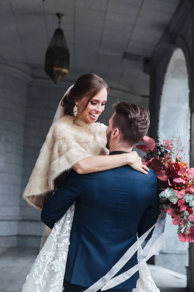 Damat gelini kollarına kaldırdı. Damat gülüp kollarında gelin.