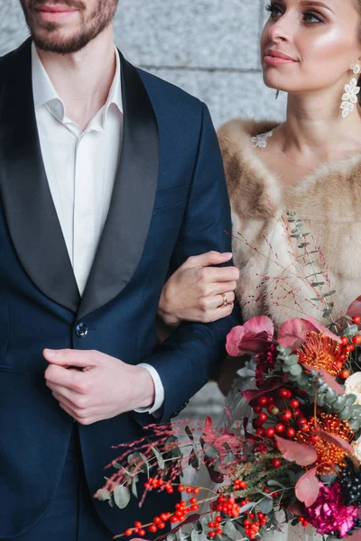 愉快的新婚夫妇摆姿势和微笑在婚纱和西服与花 — 图库照片