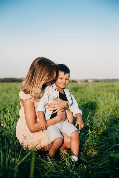 Sonriente madre y bebé sentados en el prado — Foto de Stock