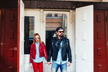 Şehir caddesinde yürüyen deri ceket ve güneş gözlüğü seksi çift