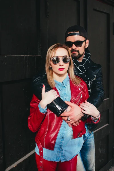 Sexy couple in leather jacket and sunglasses hugging each other on city street — Stock Photo, Image
