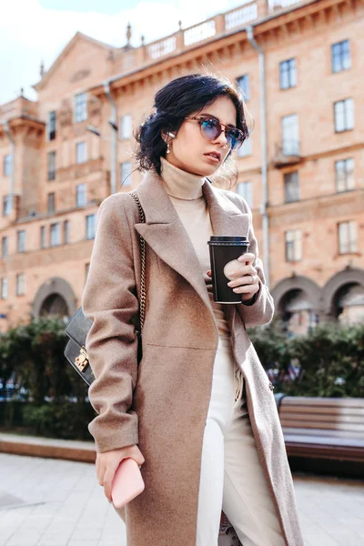 Hermosa mujer elegante en gafas de sol y abrigo con café al aire libre — Foto de Stock