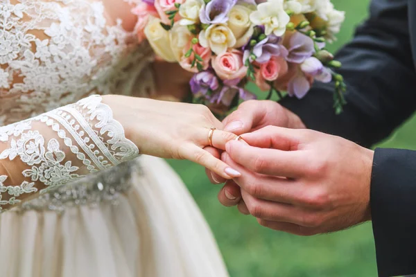 Brudgummen bär en ring på hand bruden på bröllopsceremonin utomhus — Stockfoto