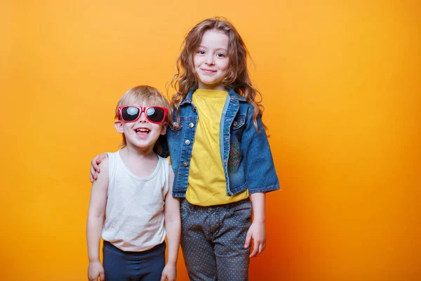 Feliz liitle hermano y hermana sobre fondo naranja — Foto de Stock