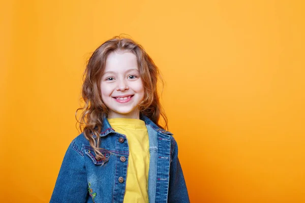 Turuncu arka plan üzerinde güzel mutlu küçük kıvırcık kız Portresi — Stok fotoğraf