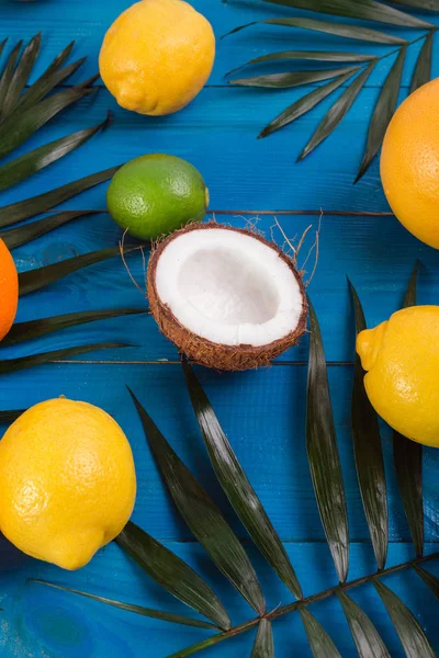 Verschiedene Früchte, grüne Blätter auf blauem Holztisch. tropischen Sommer Hintergrund mit — Stockfoto