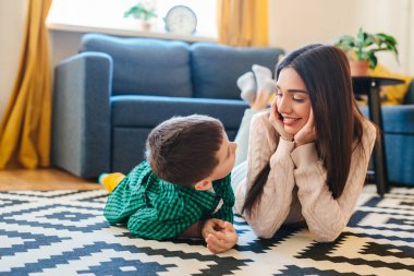 Genç anne ve küçük oğlu birbirlerine bakıyor ve yerde yatıyorlar.
