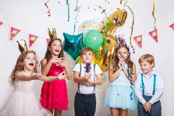 Grupo de crianças jogando confete colorido e olhando feliz na festa de aniversário — Fotografia de Stock