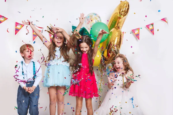 Grupa dzieci rzucających kolorowe konfetti i patrząc szczęśliwy na urodziny — Zdjęcie stockowe