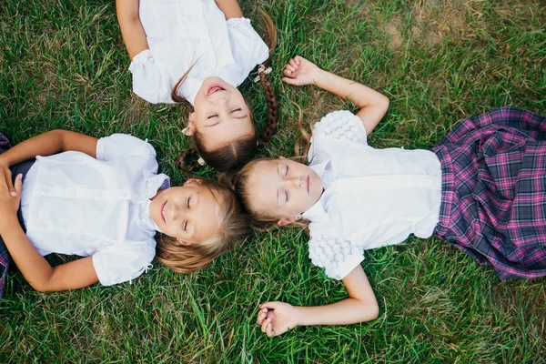 De vuelta a la escuela. Grupo de niñas lindas de la escuela primaria tumbadas en el patio de la escuela . — Foto de Stock