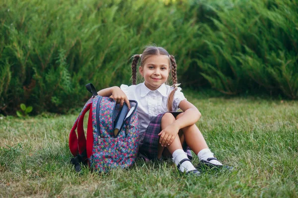 Zurück zur Schule. Nettes kleines Mädchen aus der Grundschule sitzt auf dem Schulhof. — Stockfoto